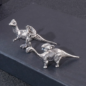 Detailed macro view of vintage silver dinosaur pendants in parasaurolophus and brontosaurus shapes
