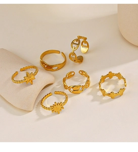Detailed view of six gold-plated adjustable rings featuring star and sun motifs on beige background