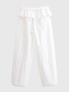 Détail d'un pantalon blanc large à taille haute avec un design à volants superposés