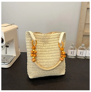 Detailed shot of rainbow straw tote bag with wooden bead handle on a black tabletop