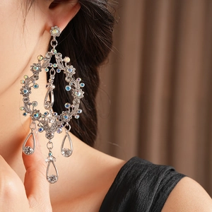 Detailed view of silver dripping tassel earrings with sparkling crystals on a model's ear