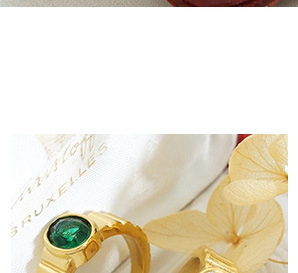 Detail of 18K gold plated ring featuring green gemstone and grooved texture design
