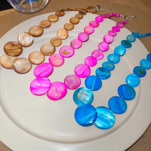 Detail of round shell bead necklaces in four colors with natural mother-of-pearl texture