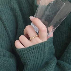 Detail shot of a minimalist gold geometric faceted ring worn on a model's finger