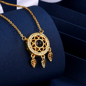 Golden dreamcatcher necklace with zircon projection stone and leaf charms on blue velvet