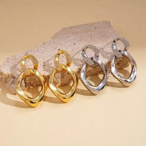 Interlocking geometric twist earrings in gold and silver set with zircon on stone