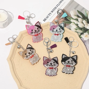 Detailed view of colorful rhinestone cat keychains with tassels and bells on a tray