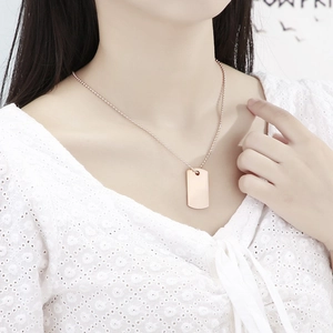 Elegante collana con piastrina rettangolare in oro rosa e catena a sfere indossata da modella