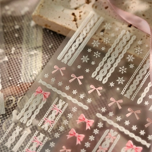 Macro view of 3D embossed nail stickers featuring pink bows and white cable knit patterns