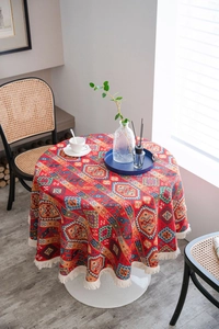 Detail of round red jacquard tablecloth with colorful geometric patterns and white tassels