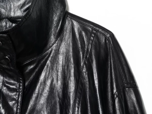 Detail shot of black faux leather bomber jacket collar and stitching on white background