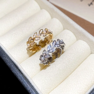 Detailed view of gold and silver wheat leaf rings with zircon and pearls in a velvet box