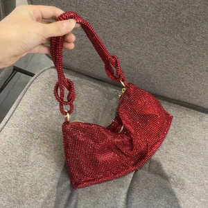 Close-up of red rhinestone evening clutch bag with unique knotted handle design