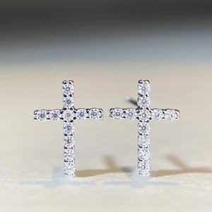 Macro detail of cross stud earrings featuring pavé-set shimmering stones in silver finish