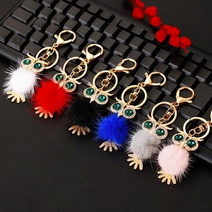 Detailed view of rhinestone owl keychains with colorful plush balls and gold metal rings