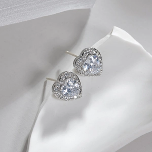 Macro shot of heart-shaped silver earrings with sparkling cubic zirconia on a white tray