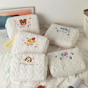 Detail of white quilted cosmetic bags with puppy embroidery and colorful handles