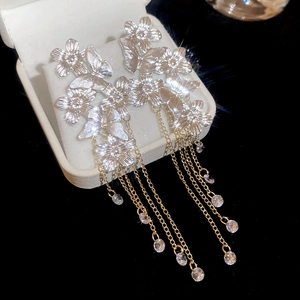 Detail of silver butterfly flower earrings with long gold chain tassels and clear zircons