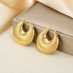 Macro shot of gold-plated U-shaped earrings with shell texture on a premium jewelry box