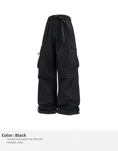 Detalle de pantalones cargo negros con cintura elástica, hebilla y bolsillo lateral con cremallera