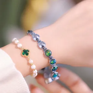 Elegant pearl bracelet with clover pendant and silver link bracelet set on model's wrist