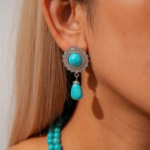 Detail of bohemian turquoise drop earrings with sunflower sunburst silver design on model