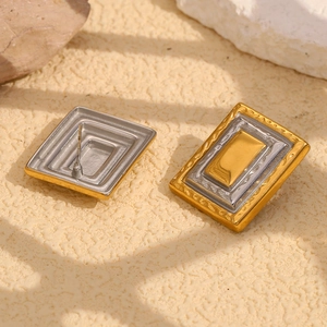 Detail of rectangular two-tone 18K gold plated geometric frame studs on a stone texture