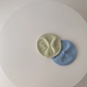 Baby knit beret hats in pastel green and blue colors for autumn on white table