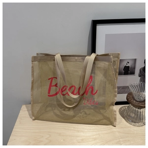 Macro detail of beige mesh beach tote bag with red Beach Vibes cursive print on front