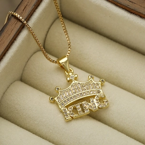 Macro shot of gold-plated crown KING pendant with cubic zirconia stones in a jewelry box