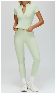 Detail of mint green half-zip short sleeve top and high-waist yoga leggings