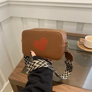 Brown crossbody camera bag with red heart pattern and wide geometric shoulder strap