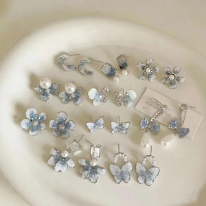 Blue gradient glass bead and pearl flower butterfly earring set in a white ceramic dish