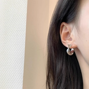 Close-up of model wearing silver twisted metal hoop earring with unique spiral texture