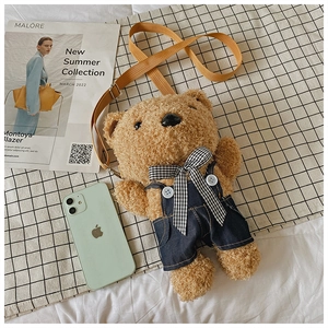Detail of cute brown plush teddy bear crossbody bag with denim overalls and adjustable strap