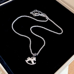Macro shot of silver rocking horse pendant with hammered texture and fine chain