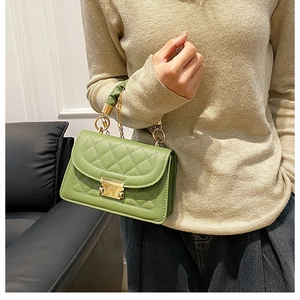 Detalle de bolso acolchado verde con elegantes herrajes dorados y asa fruncida