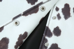 Détail du tissu en maille imprimé vache avec boutons-pression métalliques argentés