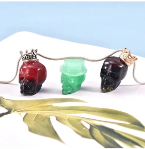 Detail of three skull pendants in red, green, and black with crown and top hat accents