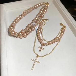Double-layer pearl necklace with sparkling diamond cross pendant in a jewelry tray