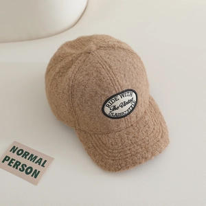 Detailed view of the brown lamb wool texture and vintage oval letter patch on the cap