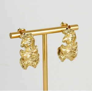 Detailed view of 18K gold plated irregular lava earrings with wavy texture on a T-stand