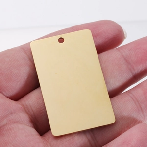 Polished gold rectangular stainless steel pet tag pendant held by hand on white background