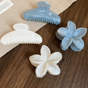 Détail de pinces à cheveux fleurs en acrylique effet marbre bleu et blanc crème