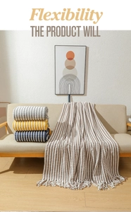 Close-up of chunky knit chenille blankets in grey and yellow on a modern sofa