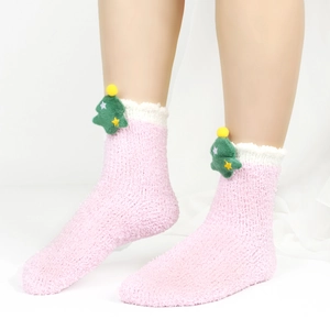 Detail eines flauschigen rosa Korallenvlies-Sockens mit 3D-Weihnachtsbaum-Verzierung