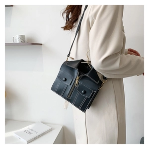 Detail shot of a black motorcycle jacket shaped crossbody bag with white stitching