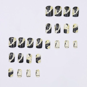 Press-on nails featuring black and white contrast design with gold splatter accents
