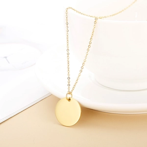 Detailed view of a polished gold circular pendant necklace on a soft minimalist background