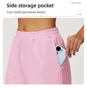 Detail of high-waisted pink sports shorts featuring large side pockets for smartphone storage